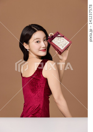 Holiday gift presentation with an elegant woman in a red dress 141237578