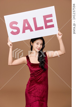 Elegant woman advertising a sale event in a studio Elegant woman advertising a sale event in a studio 141237594