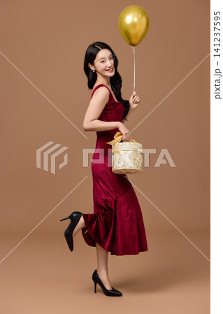 Elegant woman holding a gift basket and a gold balloon Elegant woman holding a gift basket and a gold balloon 141237595