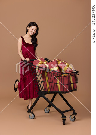 Asian woman pushing a shopping cart filled with wrapped gifts Asian woman pushing a shopping cart filled with wrapped gifts 141237606