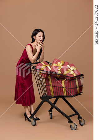 Asian woman pushing a shopping cart filled with wrapped gifts Asian woman pushing a shopping cart filled with wrapped gifts 141237622