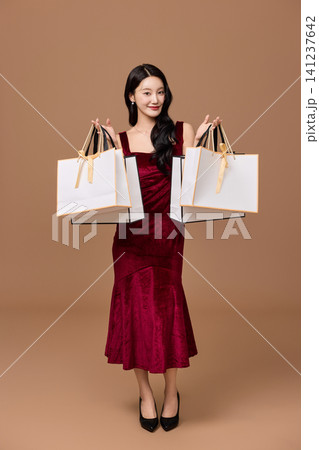 Asian woman pushing a shopping cart filled with wrapped gifts Asian woman pushing a shopping cart filled with wrapped gifts 141237642