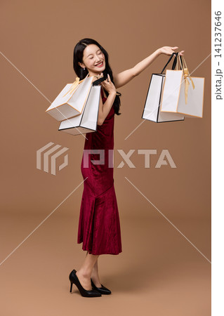 Asian woman pushing a shopping cart filled with wrapped gifts Asian woman pushing a shopping cart filled with wrapped gifts 141237646