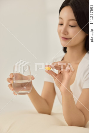 Asian woman sitting in bed with a glass of water Asian woman sitting in bed with a glass of water 141237695