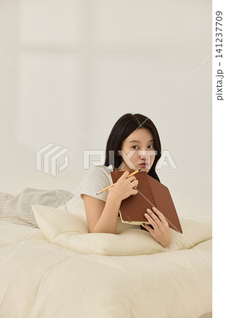 Asian woman enjoying quiet reading time in a bedroom Asian woman enjoying quiet reading time in a bedroom 141237709