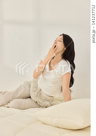 Young Asian woman waking up and stretching on a bed 141237712