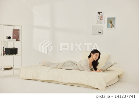 Relaxed home lifestyle portrait in a minimal white bedroom 141237741
