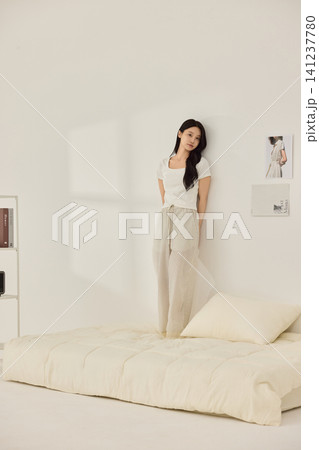 Woman stretching with a pillow in a bright minimal bedroom 141237780