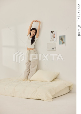 Playful morning lifestyle portrait with a woman on a cream bed Playful morning lifestyle portrait with a woman on a cream bed 141237782