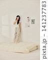 Asian woman posing with a pillow in a white bedroom 141237783