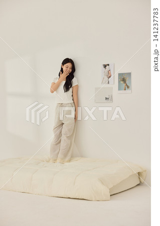 Asian woman posing with a pillow in a white bedroom 141237783
