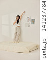 Young Asian woman standing on a bed and holding a large pillow 141237784