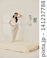Young Asian woman standing on a bed and holding a large pillow 141237788