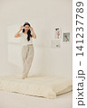 Woman stretching with a pillow in a bright minimal bedroom 141237789