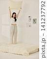 Young Asian woman standing on a bed and holding a large pillow 141237792