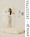 Woman stretching with a pillow in a bright minimal bedroom 141237793