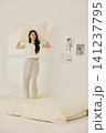 Playful morning lifestyle portrait with a woman on a cream bed 141237795