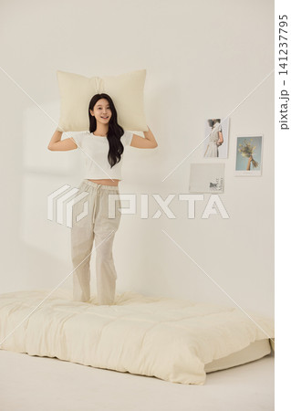 Playful morning lifestyle portrait with a woman on a cream bed Playful morning lifestyle portrait with a woman on a cream bed 141237795