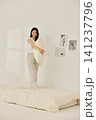 Woman stretching with a pillow in a bright minimal bedroom 141237796