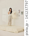 Young Asian woman standing on a bed and holding a large pillow 141237797