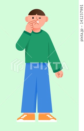 A boy stands in a basic green background. He makes a funny face and holds his nose with one hand. The boy looks to be in a playful mood. 141237991
