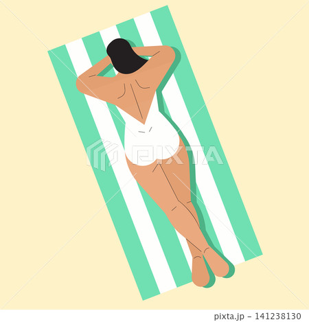 A person is lying on a green and white striped towel by the beach. The sun is shining brightly, and it is daytime. The individual is relaxing in a swimsuit. 141238130