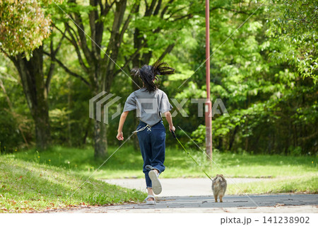 春の公園で可愛いポメラニアンの子犬を抱っこして散歩する私服の十代の女の子の姿 春の公園で可愛いポメラニアンの子犬を抱っこして散歩する私服の十代の女の子の姿 141238902