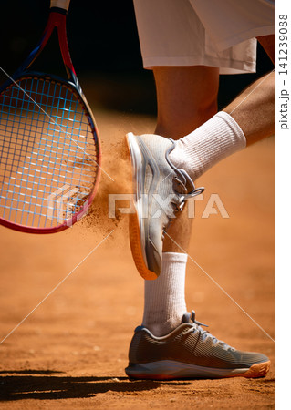 Tennis footwear and racket detail with clay dust during court step. Tennis footwear and racket detail with clay dust during court step. 141239088