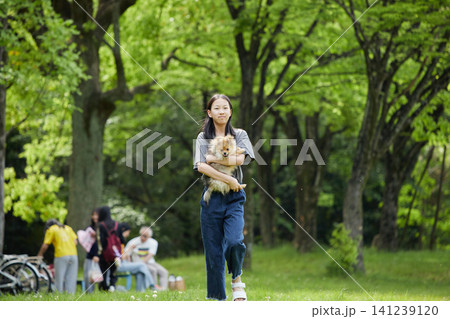 春の公園で楽しく可愛いポメラニアンの子犬と散歩する十代の女の子の姿 春の公園で楽しく可愛いポメラニアンの子犬と散歩する十代の女の子の姿 141239120