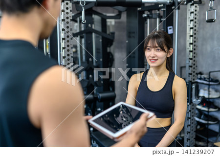 仕事帰りにジムに通う若い女性 トレーナーから説明を受ける 筋トレ女子 仕事帰りにジムに通う若い女性 トレーナーから説明を受ける 筋トレ女子 141239207