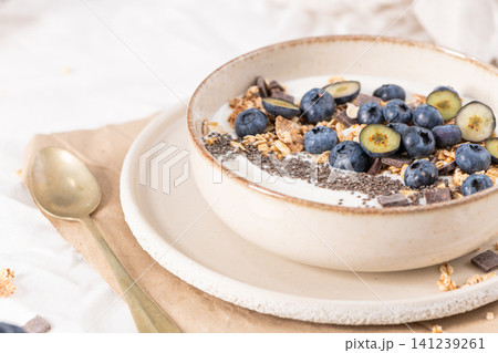 Healthy yogurt bowl with fresh blueberries, granola, and chia seeds in a rustic ceramic dish for a nutritious and delicious morning breakfast Healthy yogurt bowl with fresh blueberries, granola, and chia seeds in a rustic ceramic dish for a nutritious and delicious morning breakfast 141239261