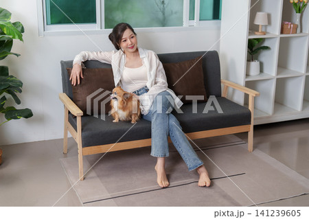 Asian woman relaxing on sofa with Chihuahua dog at home Asian woman relaxing on sofa with Chihuahua dog at home 141239605
