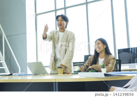 Young cheerful Asian business woman discussing project with colleagues while working together in the modern office. Young cheerful Asian business woman discussing project with colleagues while working together in the modern office. 141239650