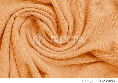 Horizontal macro close up of a soft pastel orange knitted fabric material texture twisted into a beautiful spiral swirl pattern on a warm cozy sweater Horizontal macro close up of a soft pastel orange knitted fabric material texture twisted into a beautiful spiral swirl pattern on a warm cozy sweater 141239693