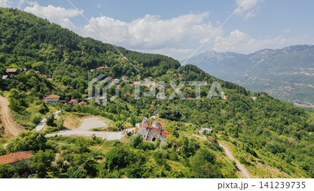 Aerial high angle view of the famous tilted church of Ropoto village near Trikala in Greece standing slanted on a green mountain hill slope after a landslide 141239735