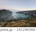 The stunning panoramic sunrise view of the turquoise acid crater lake at Mount Ijen volcano, featuring majestic rocky mountain ridges and thick sulfur smoke rising from the active vents in East Java. 141240360