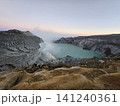 The stunning panoramic sunrise view of the turquoise acid crater lake at Mount Ijen volcano, featuring majestic rocky mountain ridges and thick sulfur smoke rising from the active vents in East Java. 141240361