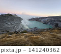 The stunning panoramic sunrise view of the turquoise acid crater lake at Mount Ijen volcano, featuring majestic rocky mountain ridges and thick sulfur smoke rising from the active vents in East Java. 141240362