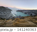 The stunning panoramic sunrise view of the turquoise acid crater lake at Mount Ijen volcano, featuring majestic rocky mountain ridges and thick sulfur smoke rising from the active vents in East Java. 141240363