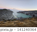 The stunning panoramic sunrise view of the turquoise acid crater lake at Mount Ijen volcano, featuring majestic rocky mountain ridges and thick sulfur smoke rising from the active vents in East Java. 141240364