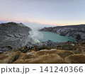 The stunning panoramic sunrise view of the turquoise acid crater lake at Mount Ijen volcano, featuring majestic rocky mountain ridges and thick sulfur smoke rising from the active vents in East Java. 141240366