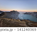 The stunning panoramic sunrise view of the turquoise acid crater lake at Mount Ijen volcano, featuring majestic rocky mountain ridges and thick sulfur smoke rising from the active vents in East Java. 141240369