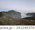 The stunning panoramic sunrise view of the turquoise acid crater lake at Mount Ijen volcano, featuring majestic rocky mountain ridges and thick sulfur smoke rising from the active vents in East Java. 141240370