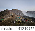 The stunning panoramic sunrise view of the turquoise acid crater lake at Mount Ijen volcano, featuring majestic rocky mountain ridges and thick sulfur smoke rising from the active vents in East Java. 141240372