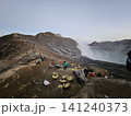 The stunning panoramic sunrise view of the turquoise acid crater lake at Mount Ijen volcano, featuring majestic rocky mountain ridges and thick sulfur smoke rising from the active vents in East Java. 141240373