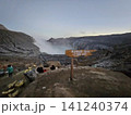 The stunning panoramic sunrise view of the turquoise acid crater lake at Mount Ijen volcano, featuring majestic rocky mountain ridges and thick sulfur smoke rising from the active vents in East Java. 141240374