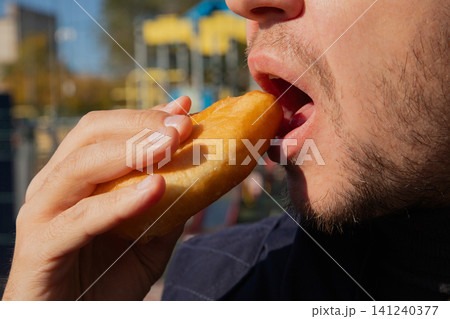 Man eating fried pastry with potato filling. Traditional Russian cuisine snack. Person tasting deep fried dough with savory stuffing outdoors at street food festival. Tasty wheat meal. Man eating fried pastry with potato filling. Traditional Russian cuisine snack. Person tasting deep fried dough with savory stuffing outdoors at street food festival. Tasty wheat meal. 141240377