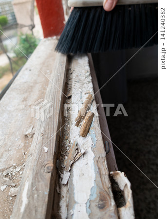 Old Wooden Window Frame with Stripped Paint and Hand Holding Cleaning Brush Old Wooden Window Frame with Stripped Paint and Hand Holding Cleaning Brush 141240382
