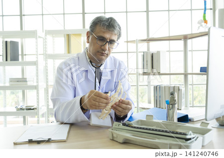 Orthopedic doctor in his office. Orthopedic doctor explain the ankle bone structure to the patient. Orthopedic doctor in his office. Orthopedic doctor explain the ankle bone structure to the patient. 141240746