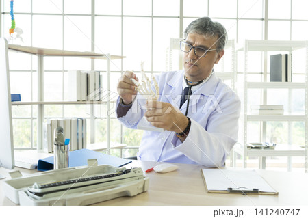 Orthopedic doctor in his office. Orthopedic doctor explain the ankle bone structure to the patient. Orthopedic doctor in his office. Orthopedic doctor explain the ankle bone structure to the patient. 141240747